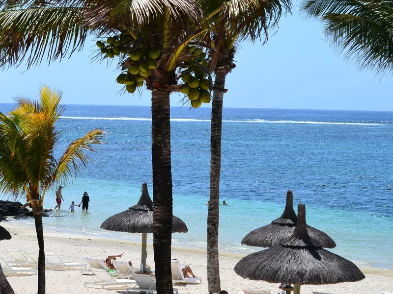 Strand mit Palmen und Strohschirmen auf Mauritius